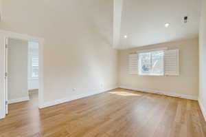 Empty room featuring high vaulted ceiling and light hardwood / wood-style flooring