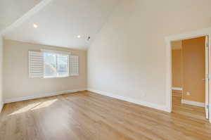 Spare room with high vaulted ceiling and light hardwood / wood-style flooring