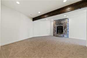 Unfurnished living room with light carpet, beam ceiling, and a fireplace