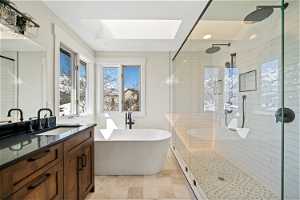 Bathroom with a skylight, oversized vanity, tile flooring, and plus walk in shower