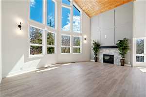 Unfurnished living room with wood ceiling, a fireplace, high vaulted ceiling, and light hardwood / wood-style flooring
