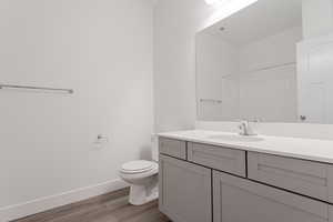 Bathroom with toilet, walk in shower, vanity, and wood-type flooring