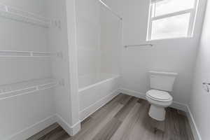 Bathroom featuring toilet, shower / bathing tub combination, and wood-type flooring