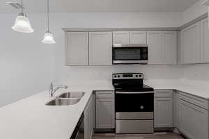 Kitchen featuring gray cabinets, stainless steel appliances, sink, and pendant lighting