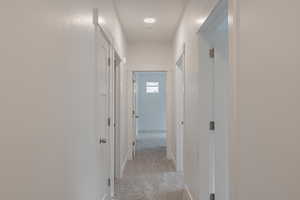 Hallway featuring light colored carpet