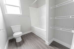 Bathroom featuring toilet, wood-type flooring, and shower / bathtub combination