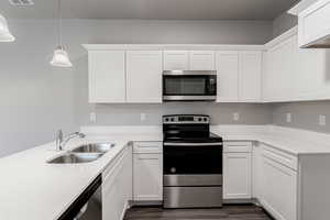 Kitchen with appliances with stainless steel finishes, white cabinetry, sink, and pendant lighting