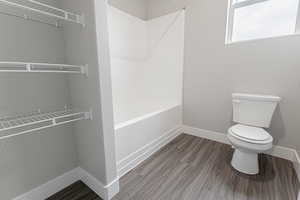 Bathroom featuring hardwood / wood-style flooring, tub / shower combination, and toilet