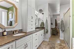 Bathroom with an enclosed shower, double sink, concrete flooring, and vanity with extensive cabinet space