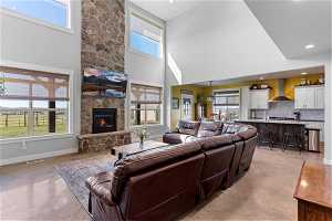 Living room featuring a high ceiling and a stone fireplace