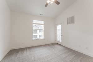 Unfurnished room featuring ceiling fan, vaulted ceiling, and carpet