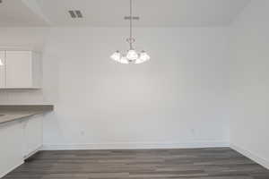 Unfurnished dining area with a chandelier and dark hardwood / wood-style floors