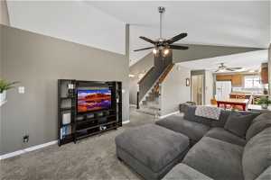 Living room featuring lofted ceiling, light colored carpet, and ceiling fan