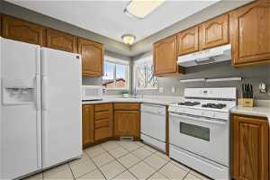 Kitchen with appliances, light tile flooring, and sink