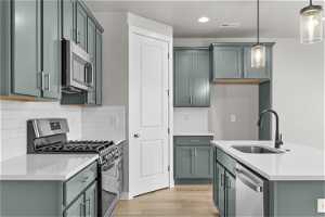 Kitchen featuring light hardwood / wood-style flooring, pendant lighting, stainless steel appliances, and sink