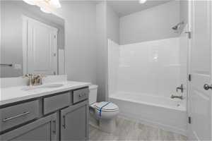 Full bathroom featuring vanity, hardwood / wood-style floors, a textured ceiling, toilet, and shower / bath combination
