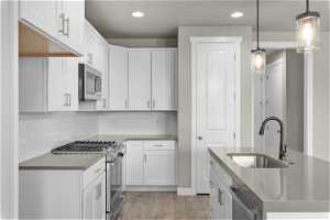 Kitchen featuring decorative light fixtures, light hardwood / wood-style floors, white cabinetry, stainless steel appliances, and sink