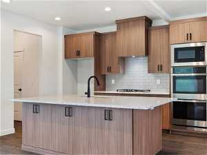 Kitchen with light stone countertops, appliances with stainless steel finishes, and dark hardwood / wood-style flooring