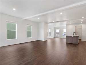 Unfurnished living room featuring dark hardwood / wood-style floors, sink, and beamed ceiling