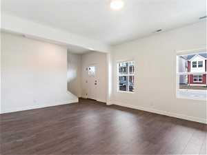 Empty room featuring dark hardwood / wood-style floors and a healthy amount of sunlight