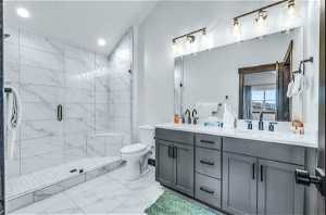 Bathroom featuring tile flooring, vaulted ceiling, dual sinks, toilet, and oversized vanity