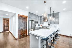 Kitchen featuring appliances with stainless steel finishes, hanging light fixtures, a breakfast bar, kitchen peninsula, and light hardwood / wood-style flooring