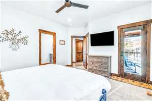Bedroom with ensuite bath, light colored carpet, ceiling fan, and access to outside