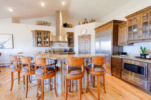 Kitchen with a kitchen bar, lofted ceiling, light wood-type flooring, and an island with sink