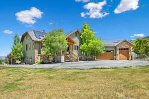 View of front of property featuring a garage, a front lawn, and solar panels