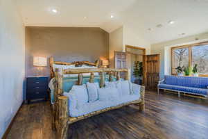 Bedroom with lofted ceiling and dark wood-type flooring