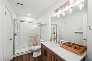 Bathroom featuring toilet, a shower with door, vanity, and hardwood / wood-style floors