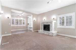 Unfurnished living room with a brick fireplace, coffered ceiling, and carpet