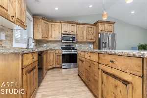 Kitchen with vaulted ceiling, stainless steel appliances, tasteful backsplash, and light hardwood / wood-style floors