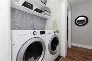 Clothes washing area with dark hardwood / wood-style floors and washing machine and clothes dryer