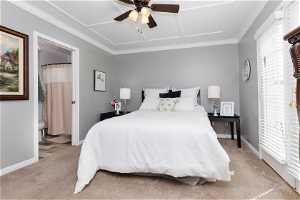 Carpeted bedroom featuring multiple windows, ceiling fan, and crown molding