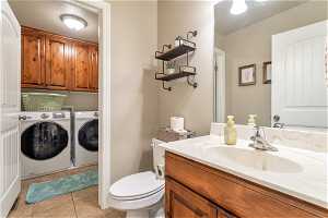 Bathroom featuring vanity, washing machine and dryer, tile floors, and toilet