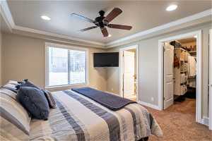 Carpeted bedroom with connected bathroom, a spacious closet, crown molding, and ceiling fan