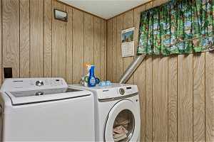 Washroom featuring washing machine and clothes dryer and wooden walls