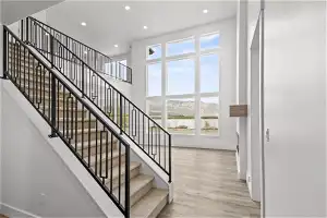 Stairs with a towering ceiling, light hardwood / wood-style floors, and a wealth of natural light