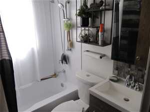 Full main bathroom with shower / tub combo with curtain, backsplash, toilet, and vanity