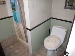 Bathroom featuring tile floors, toilet, and a shower with curtain