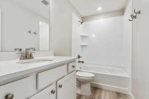 Full bathroom with tiled shower / bath, toilet, vanity, and hardwood / wood-style floors