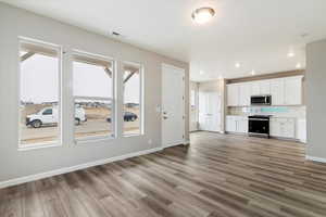 Unfurnished living room with wood-type flooring and a wealth of natural light