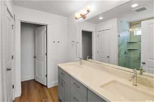 Bathroom with dual bowl vanity and wood-type flooring