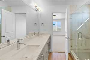 Bathroom featuring double sink vanity, an enclosed shower, and hardwood / wood-style flooring