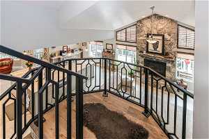 Stairway featuring  the view of stone fireplace below and kitchen, vaulted ceiling, and light hardwood / wood-style floors