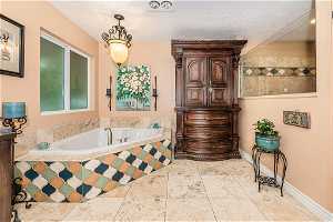 Master Bathroom featuring tiled bath, tile flooring, and a textured ceiling