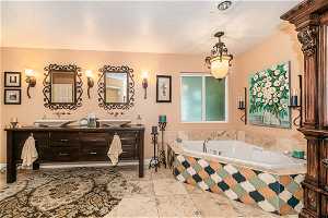 Primary Bathroom with a textured ceiling, tile flooring, double vanity, and a relaxing tiled bath