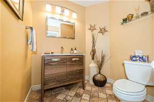 half-Bathroom with vanity, toilet, and tile floors
