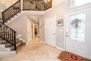 Tiled entrance foyer with a high ceiling view towards half bath, laundry and Primary Bedroom.